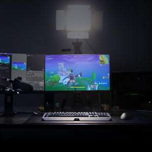  A gaming setup on a desk including a microphone and two monitors, with one monitor running a game and the other showing a streaming software interface  